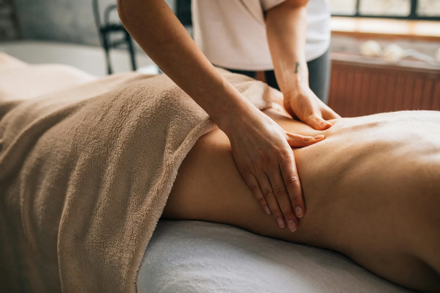 Massagem profissional nas costas de uma pessoa coberta com toalhas